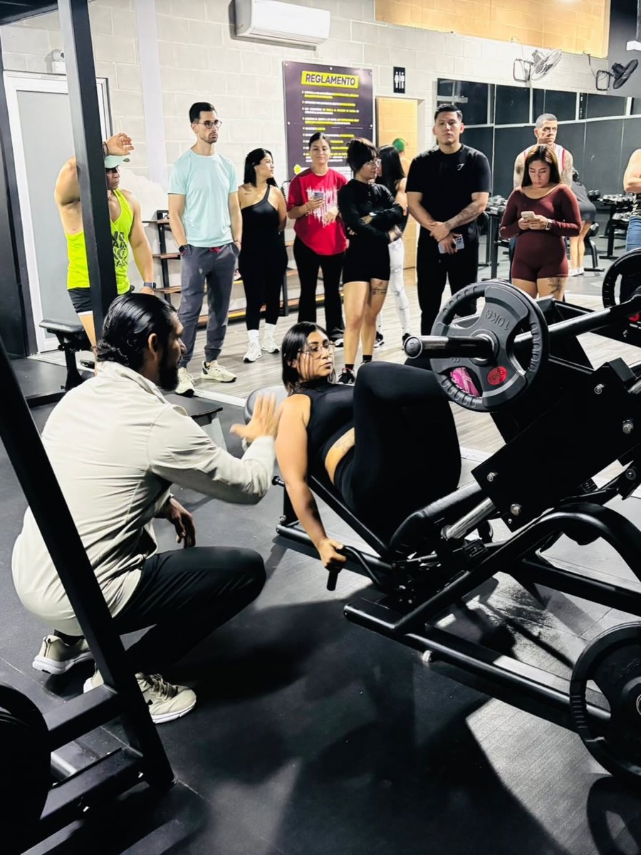 Miguel corrigiendo la técnica de una alumna en la prensa durante una clase práctica