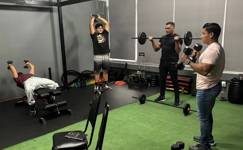 Adultos de distintas edades entrenando con mancuernas y barra bajo supervisión