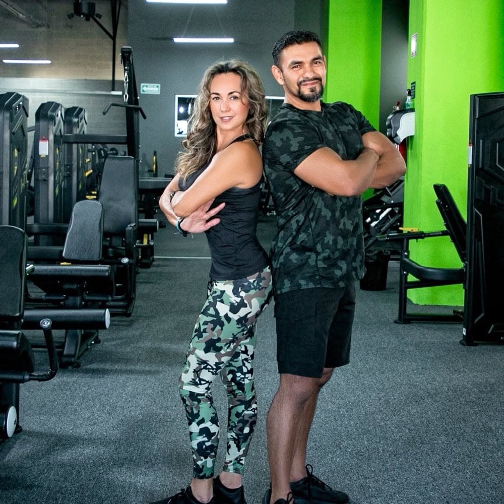 Miguel y Gaby Butt, coach certificada del equipo, espalda con espalda en el gimnasio