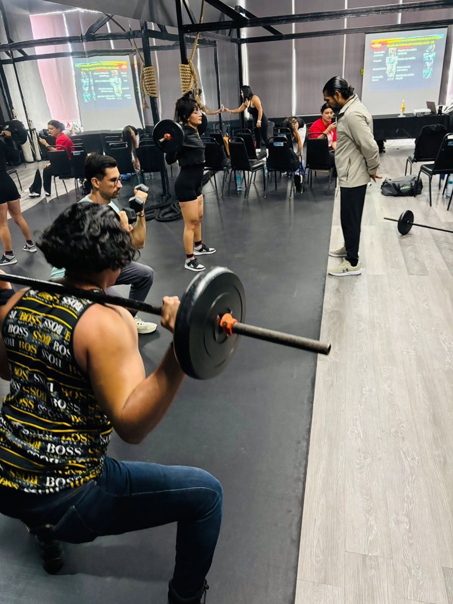 Alumnos practicando levantamientos con barra durante una clase
