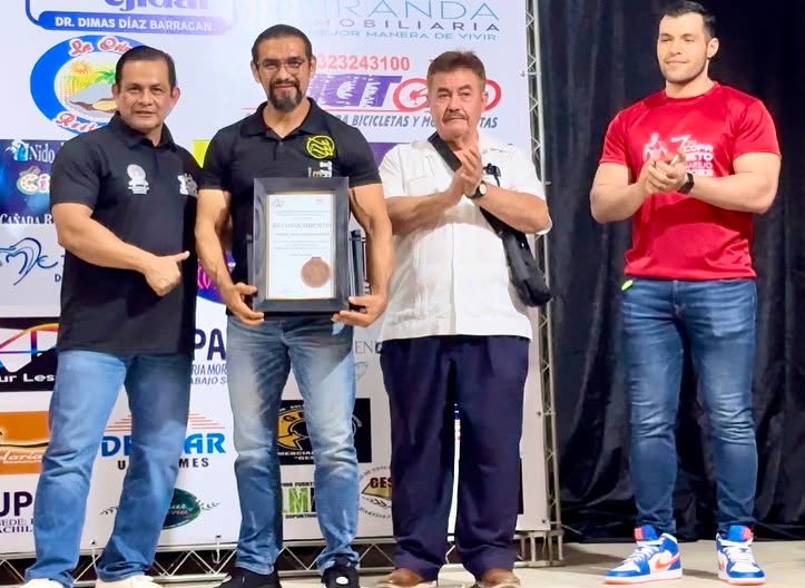 Miguel recibiendo un reconocimiento enmarcado en un evento